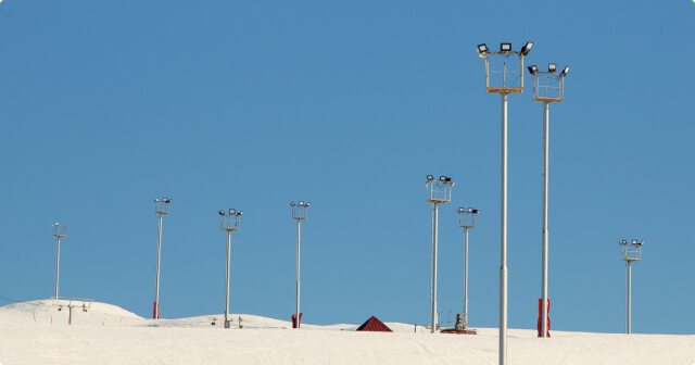 Eine Flutlichtanlage in den Bergen mit schneebedeckter Skipiste.